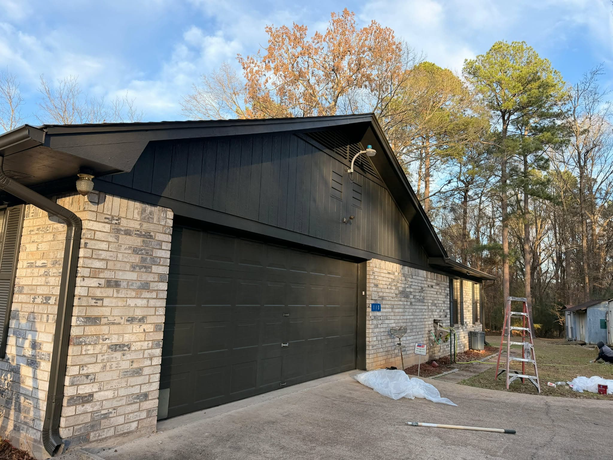 After — freshly painted dark siding and garage door on brick home